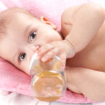 3 months adorable  baby girl drinking from plastic bottle in her