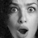 Black and white close up of a frightened astonished woman with w
